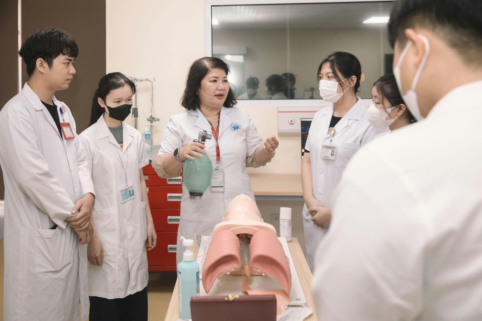 Academics Group of medical students practicing skills with a training mannequin in a classroom setting.