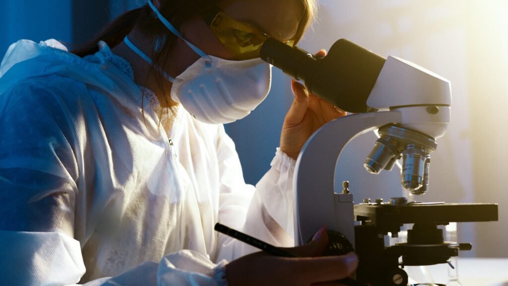 Courses A female scientist uses a microscope in a laboratory, focusing intently on her research.