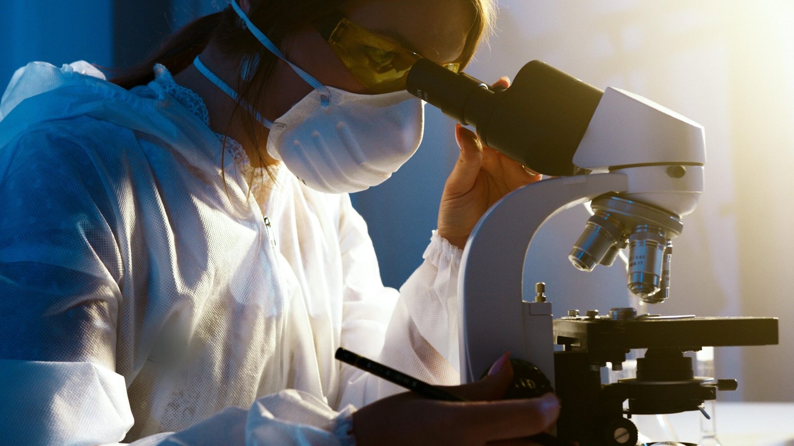 Home A female scientist uses a microscope in a laboratory, focusing intently on her research.