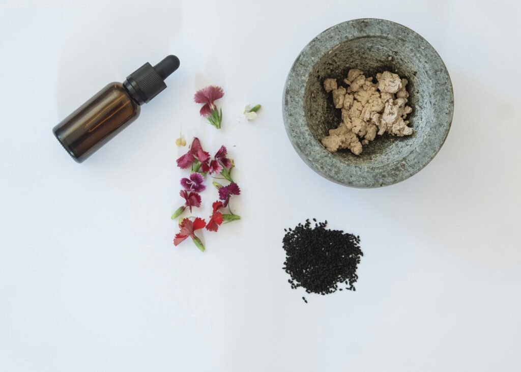 Diploma Courses Flat lay of natural skincare ingredients including flowers, black seeds, and a dropper bottle.