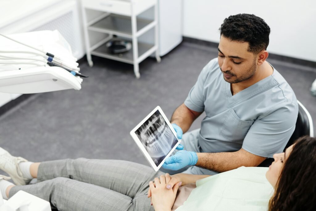 Dentist showing dental x-ray on tablet to a patient in modern clinic setting.